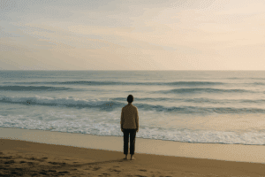 Person standing calmly on a beach, watching waves, symbolising that healing is not linear