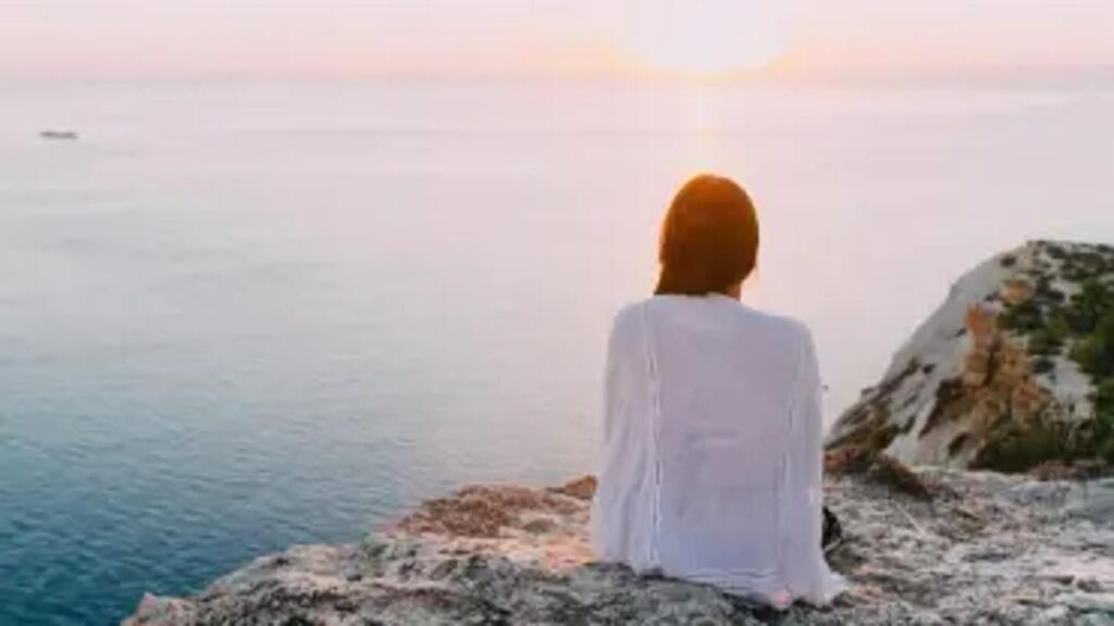 A woman sitting alone in warm natural light, processing emotions after the holidays.